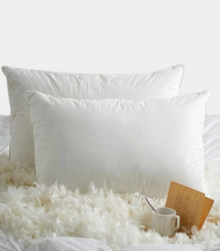 a white pillow and a mug on a bed